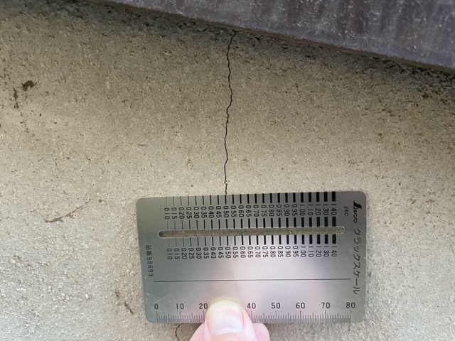 クラックスケールで基礎の危険なひび割れ幅(0.5mm以上)を計測する点検作業